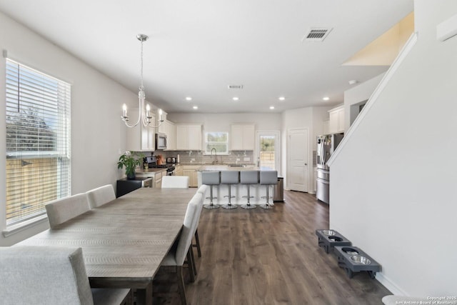 dining space featuring an inviting chandelier, sink, and dark wood-type flooring