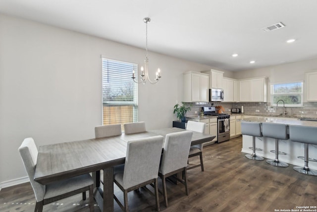 dining area with dark hardwood / wood-style flooring, sink, a notable chandelier, and a wealth of natural light