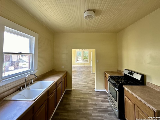 kitchen featuring stainless steel gas range oven, sink, dark wood-type flooring, and wood ceiling