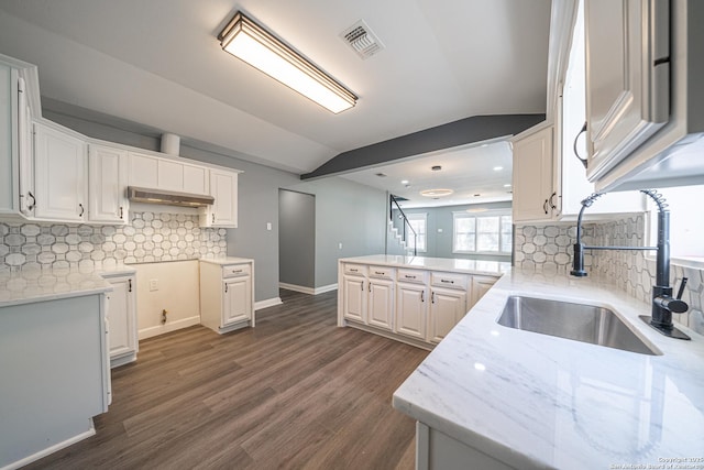 kitchen with lofted ceiling, sink, dark hardwood / wood-style floors, kitchen peninsula, and white cabinets