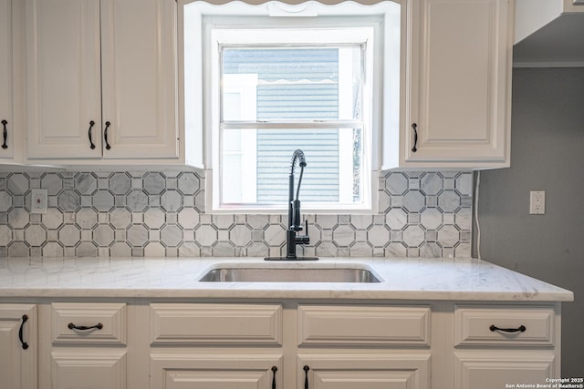 kitchen featuring tasteful backsplash, sink, light stone counters, and white cabinets