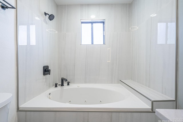 bathroom featuring tiled shower / bath combo and toilet