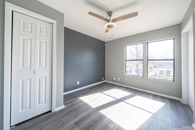 unfurnished bedroom with dark hardwood / wood-style flooring, ceiling fan, and a closet