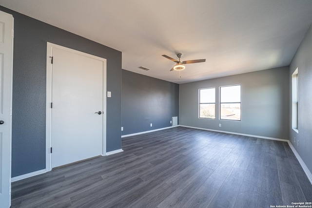 empty room with ceiling fan and dark hardwood / wood-style flooring