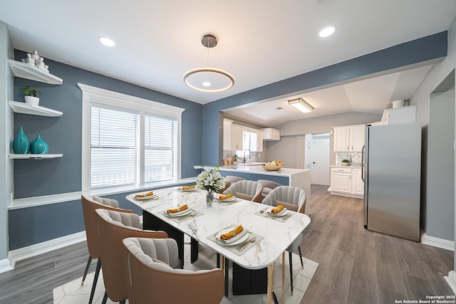 dining area featuring sink, vaulted ceiling, and dark hardwood / wood-style floors