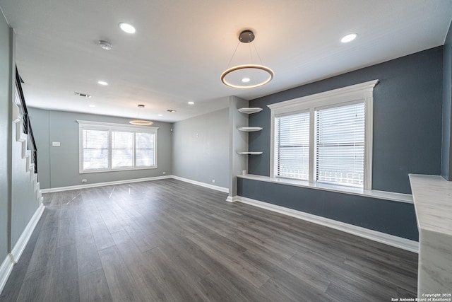 unfurnished living room with a healthy amount of sunlight and dark wood-type flooring