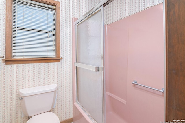 bathroom featuring a shower with shower door and toilet