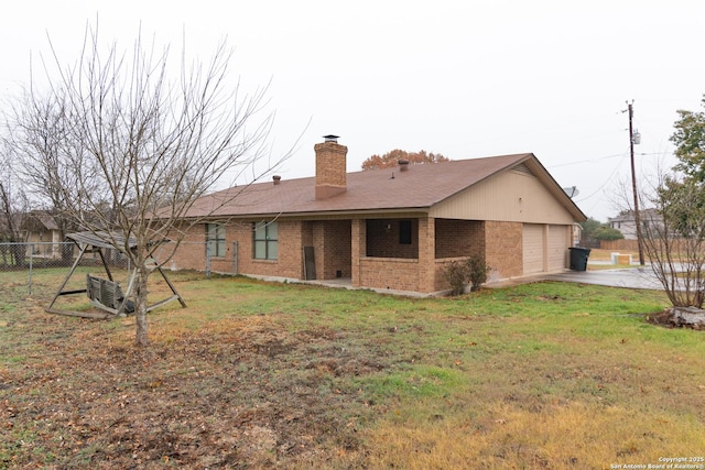 rear view of property with a garage and a yard