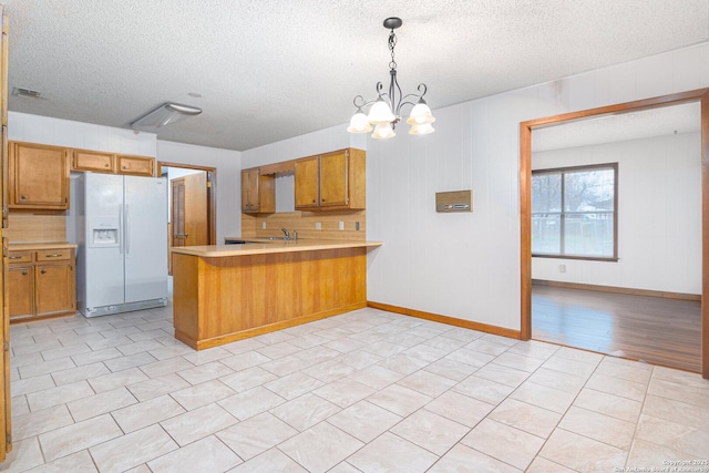 kitchen with white fridge with ice dispenser, pendant lighting, a textured ceiling, and kitchen peninsula