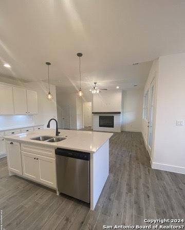 kitchen featuring white cabinetry, pendant lighting, dishwasher, and a center island with sink