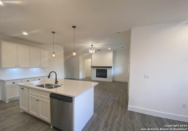 kitchen with white cabinetry, dishwasher, sink, and a center island with sink