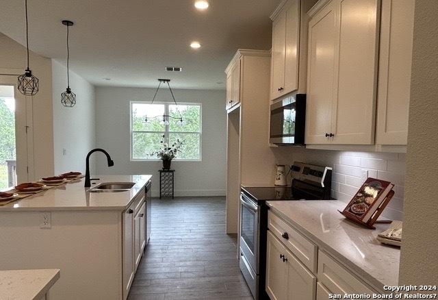 kitchen with white cabinetry, sink, decorative light fixtures, and stainless steel appliances