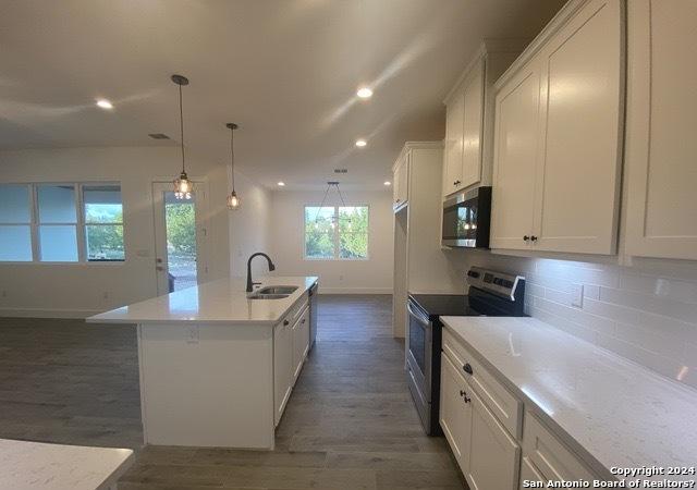 kitchen with white cabinetry, appliances with stainless steel finishes, a kitchen island with sink, and sink