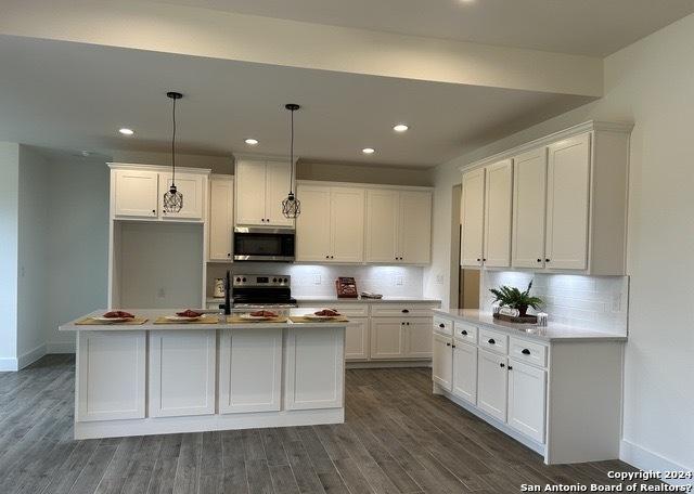 kitchen with white cabinetry, decorative light fixtures, and stainless steel appliances