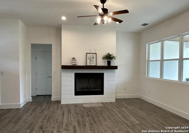 unfurnished living room featuring dark wood-type flooring and ceiling fan