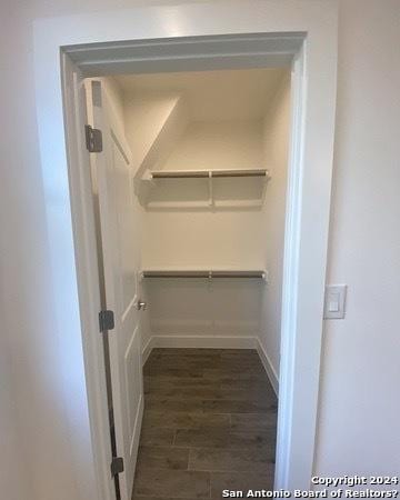 walk in closet with dark hardwood / wood-style floors