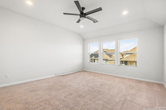 empty room with vaulted ceiling, ceiling fan, and carpet flooring