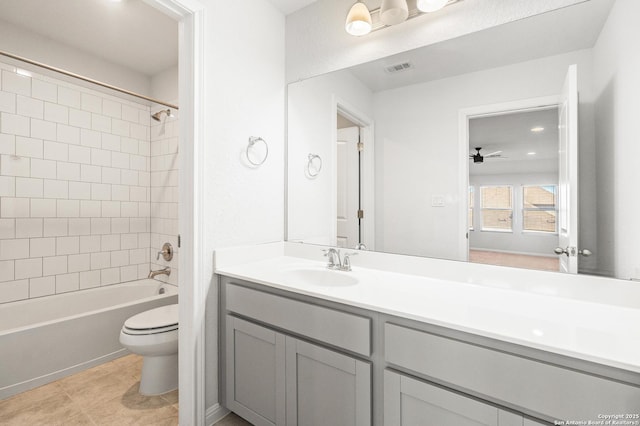 full bathroom featuring ceiling fan, tile patterned flooring, tiled shower / bath combo, vanity, and toilet