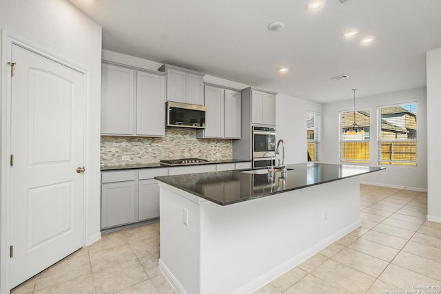 kitchen featuring gray cabinets, stainless steel appliances, and a center island with sink