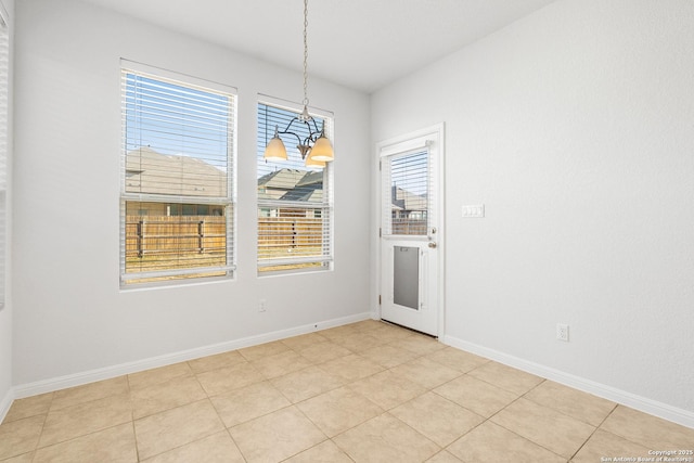 unfurnished dining area with an inviting chandelier and light tile patterned floors