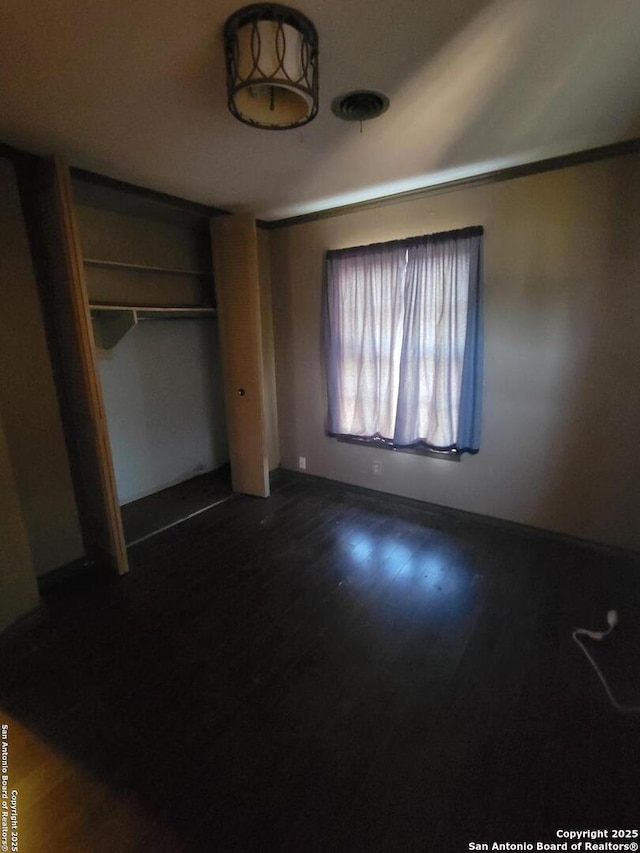 unfurnished bedroom featuring dark wood-type flooring and a closet