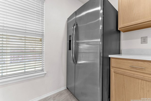 kitchen with light tile patterned floors, light brown cabinetry, and stainless steel fridge with ice dispenser