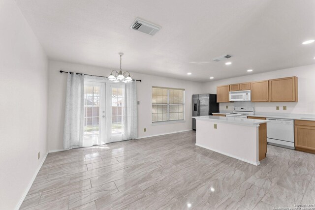 kitchen featuring hanging light fixtures, a kitchen island, a chandelier, and white appliances