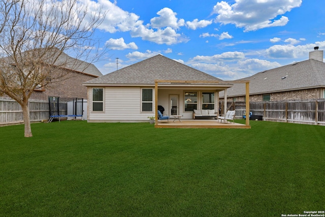 back of house featuring a trampoline, a lawn, and a patio