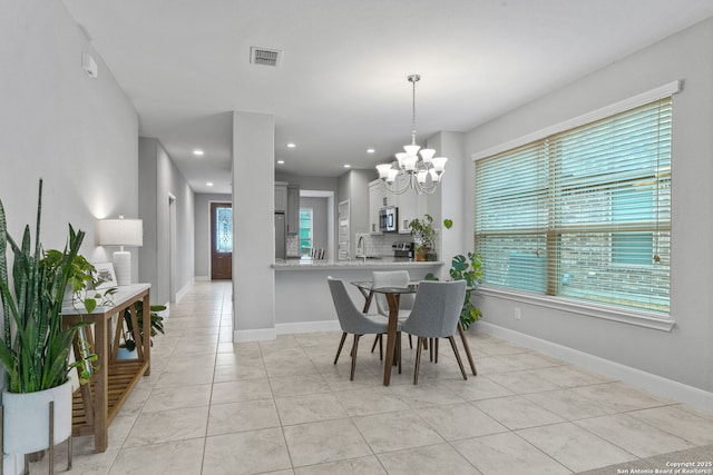 tiled dining area featuring an inviting chandelier and sink