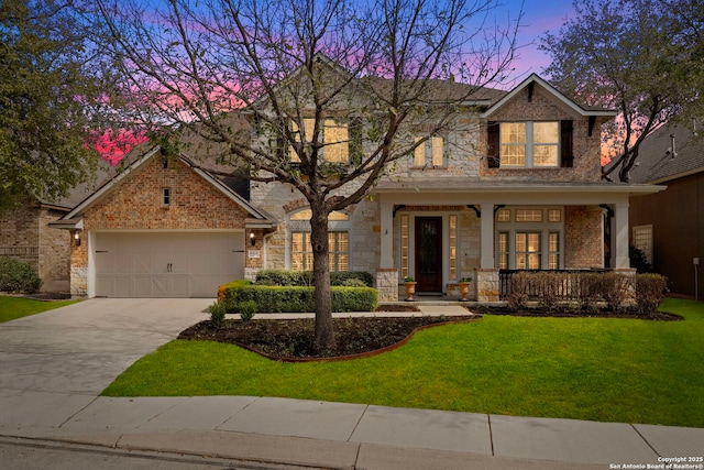 view of front of home with a porch, a garage, a yard, stone siding, and driveway