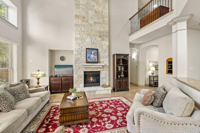 living area with a high ceiling and a stone fireplace