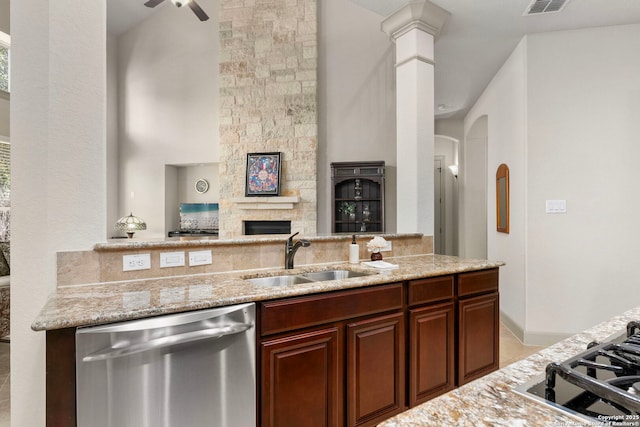 kitchen with light stone counters, open floor plan, a sink, a fireplace, and stainless steel dishwasher