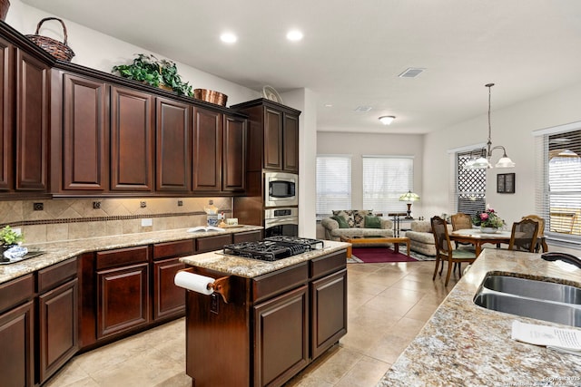 kitchen featuring pendant lighting, backsplash, appliances with stainless steel finishes, open floor plan, and a sink