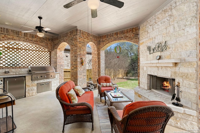 view of patio / terrace with an outdoor living space with a fireplace, a grill, and an outdoor kitchen