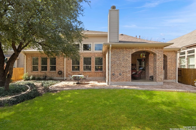 back of property with a patio, brick siding, fence, a lawn, and a chimney