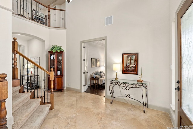 entryway with arched walkways, visible vents, stairway, a high ceiling, and baseboards