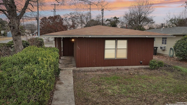 property exterior at dusk featuring cooling unit and a lawn