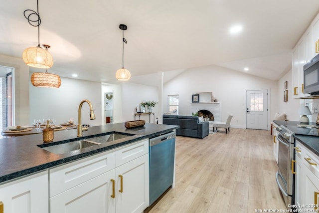 kitchen featuring white cabinetry, sink, decorative light fixtures, and stainless steel appliances