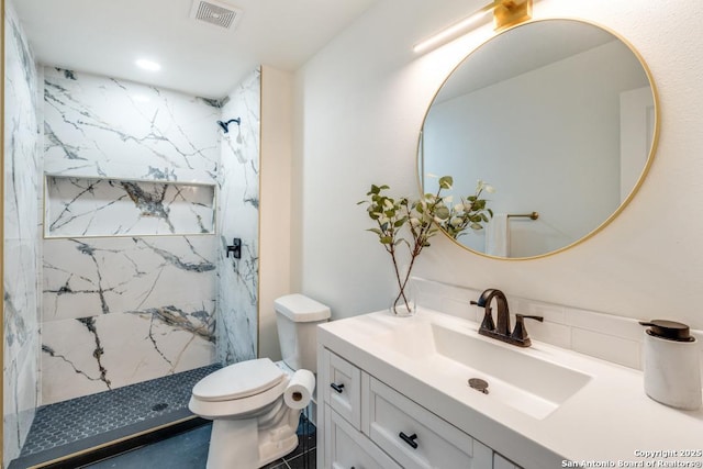 bathroom featuring tiled shower, vanity, and toilet