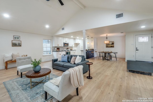 living room with beam ceiling, high vaulted ceiling, and light hardwood / wood-style floors