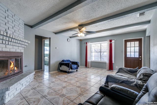 tiled living room with ceiling fan, beam ceiling, a fireplace, and a textured ceiling