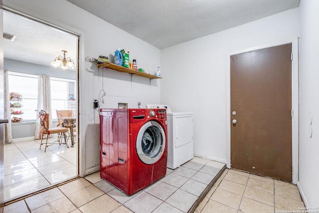 clothes washing area featuring a chandelier, washer and dryer, a textured ceiling, and light tile patterned flooring