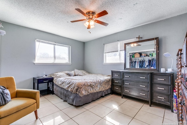 tiled bedroom with ceiling fan and a textured ceiling