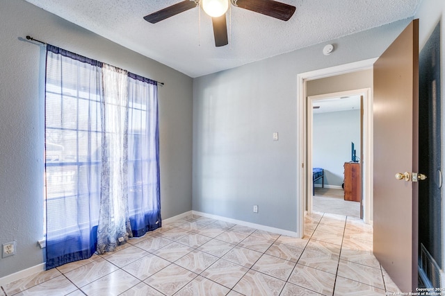 spare room featuring ceiling fan, a textured ceiling, and light tile patterned floors