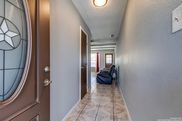 hallway featuring a textured ceiling and light tile patterned floors