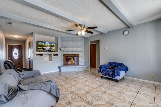 living room featuring beam ceiling, light tile patterned floors, ceiling fan, a brick fireplace, and a textured ceiling