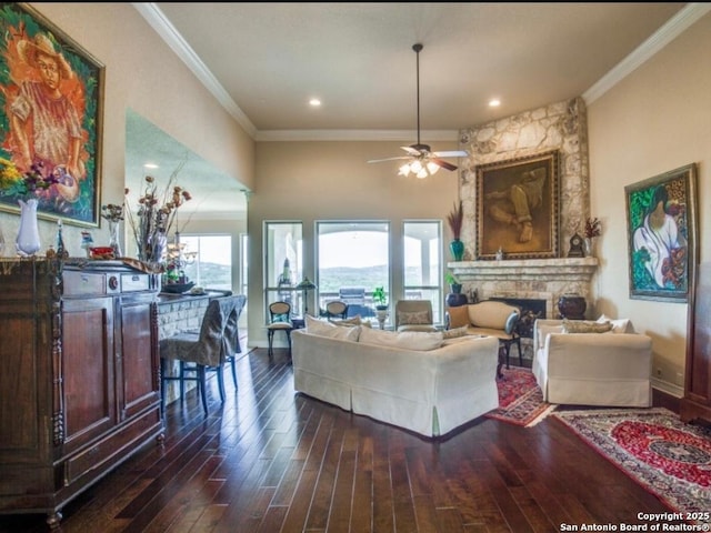 living room featuring ceiling fan, a fireplace, ornamental molding, and dark hardwood / wood-style floors