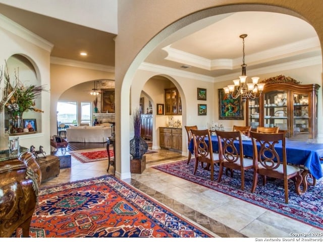 dining space featuring ornamental molding, a tray ceiling, and ceiling fan with notable chandelier