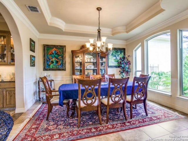 tiled dining area featuring an inviting chandelier, a tray ceiling, and ornamental molding