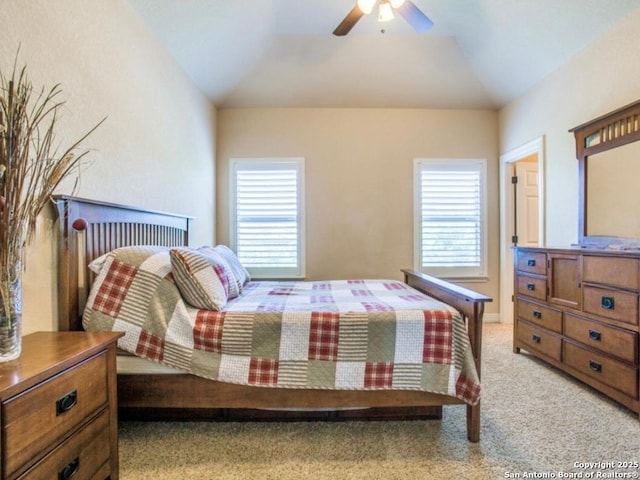 bedroom with ceiling fan, light colored carpet, and vaulted ceiling